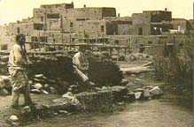 Photo of early Mexican people with dwellings in the background